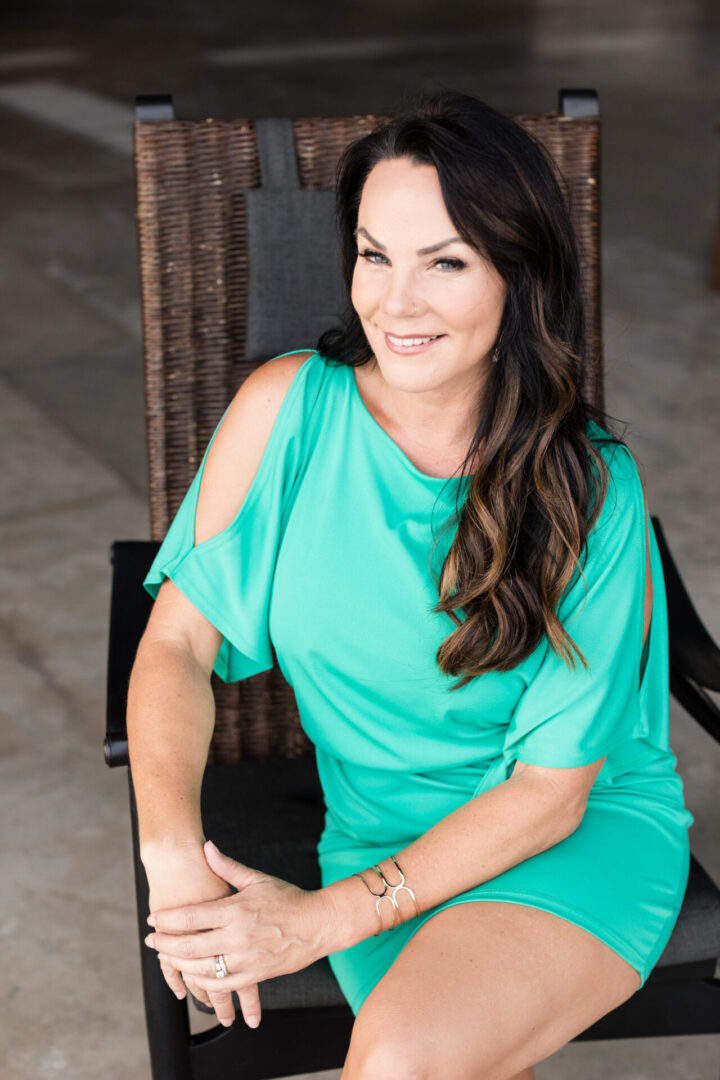 A woman sitting on top of a chair wearing a green dress.