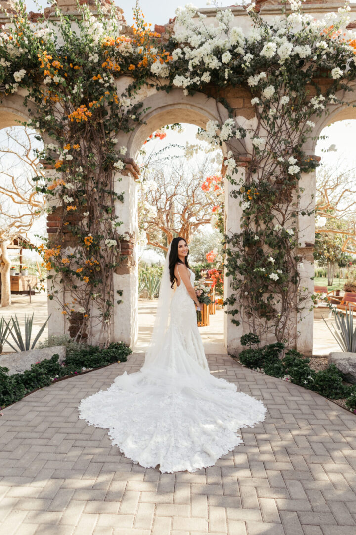A bride in her wedding dress standing under an arch.