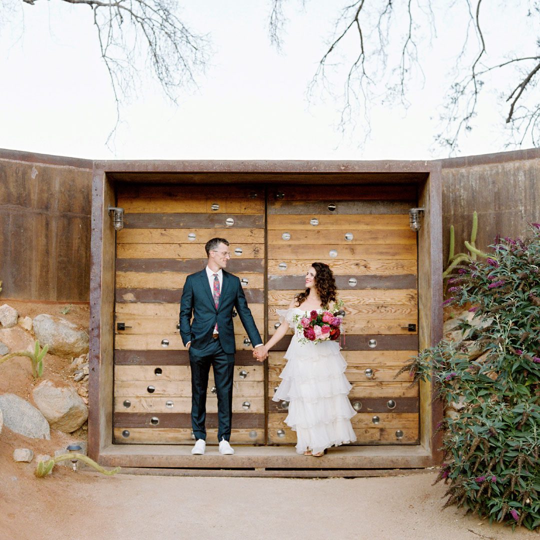 A man and woman standing in front of a wooden door.