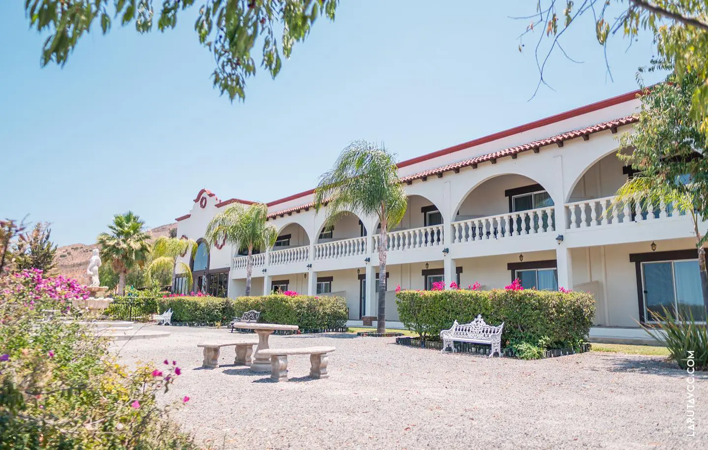 A white building with benches in front of it.