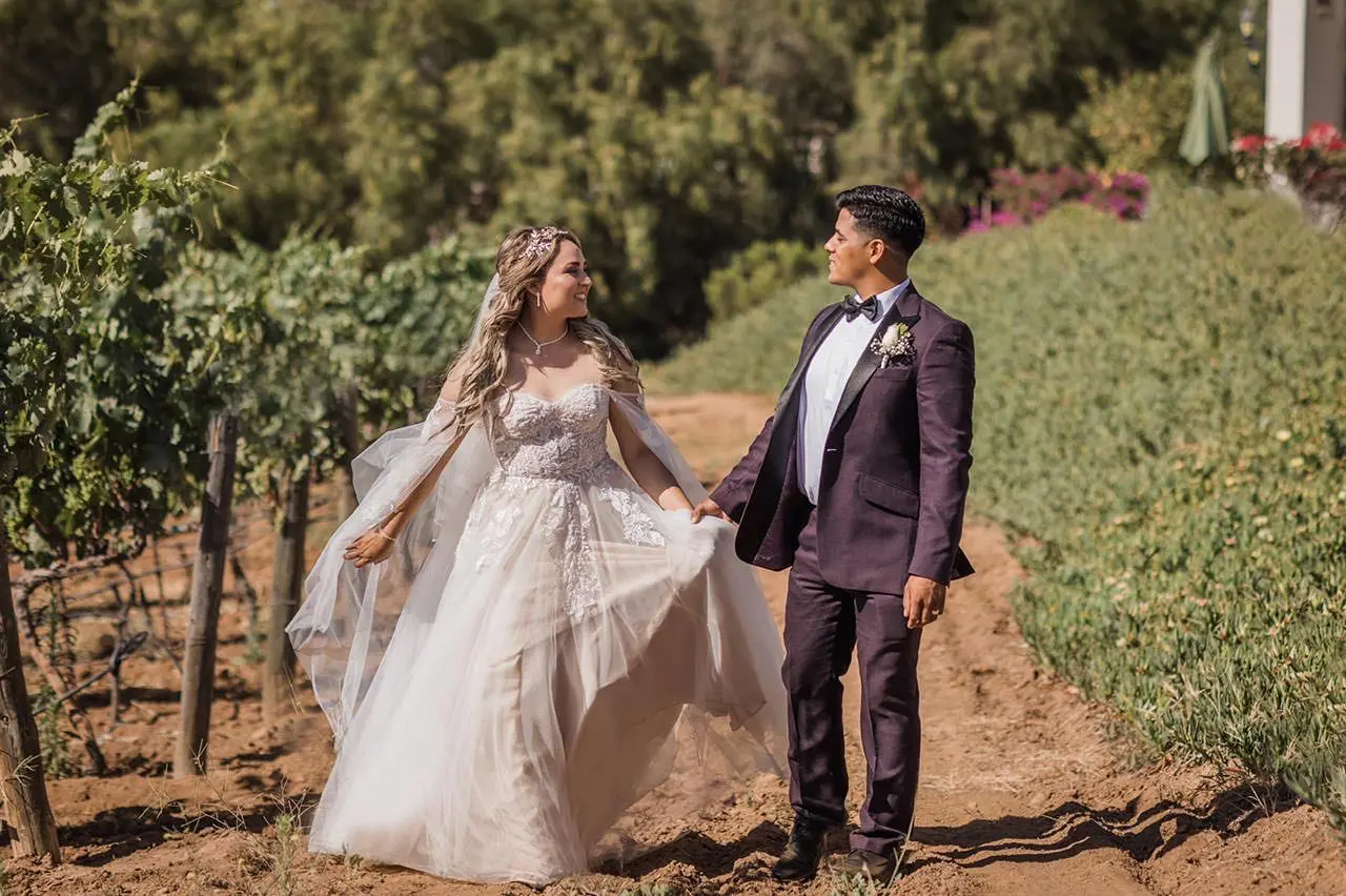 A man and woman holding hands while standing on top of a hill.