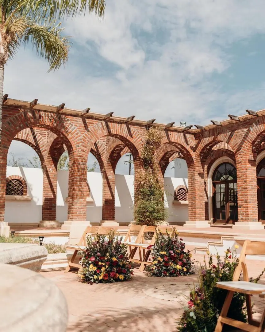 A large brick building with arches and plants.