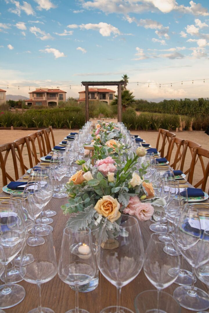 A long table with many glasses and flowers on it