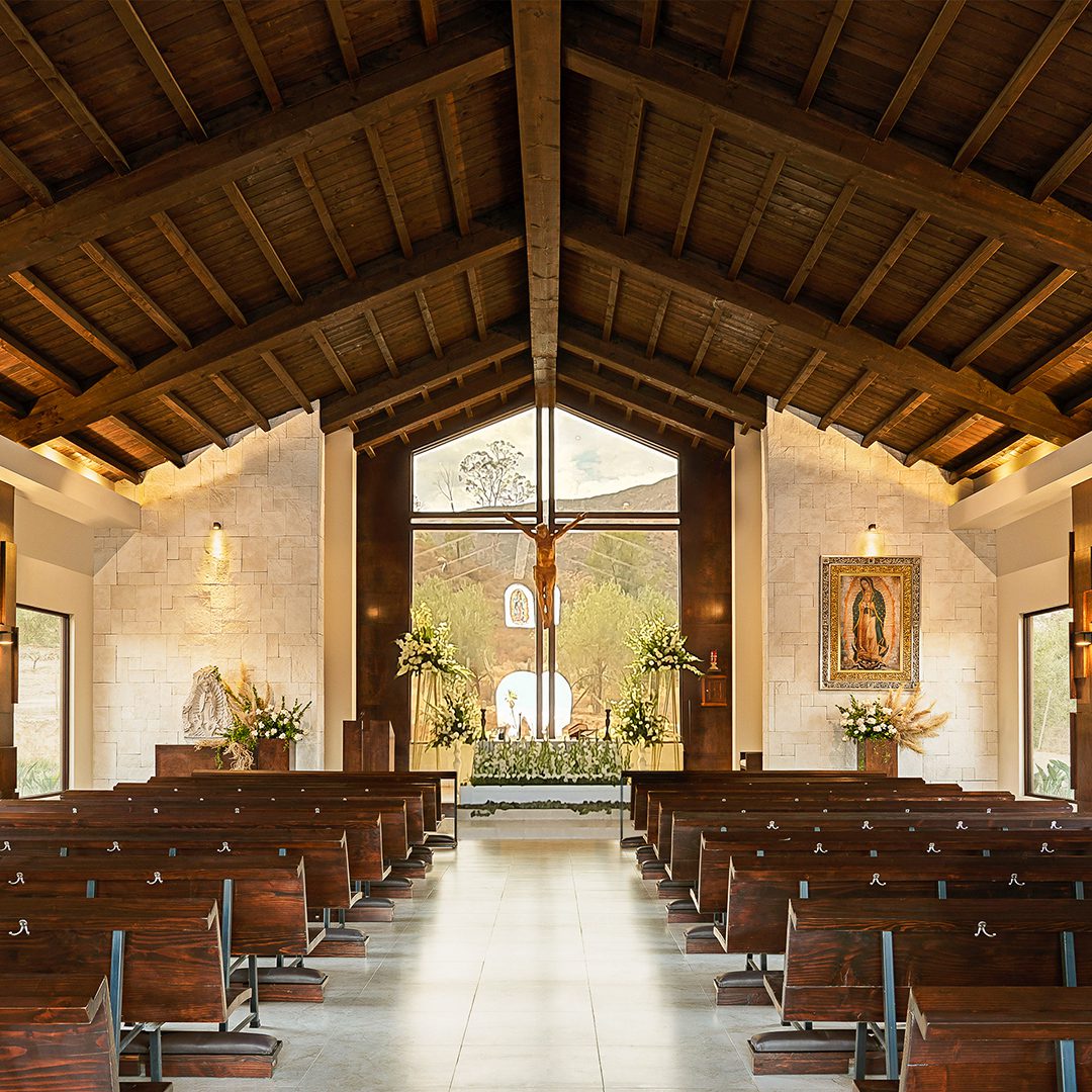 A church with many wooden pews and a cross in the center.