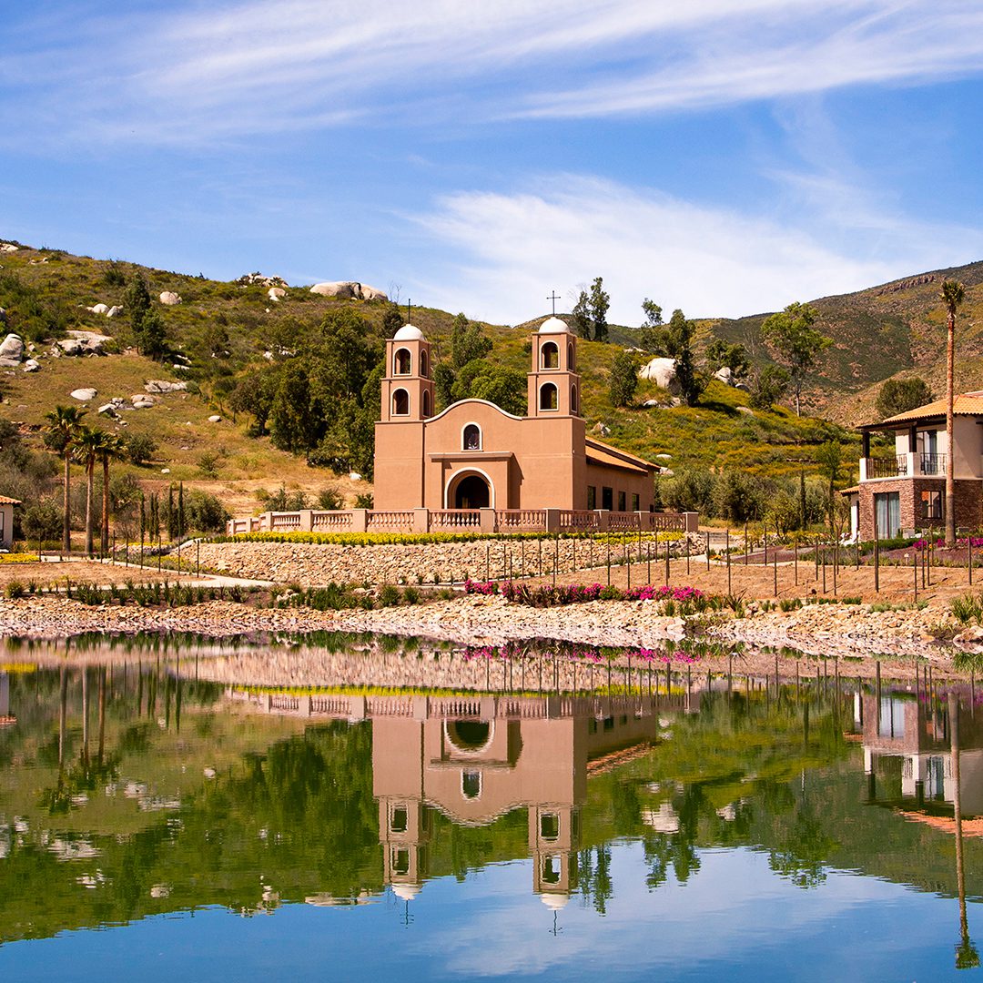A church is reflected in the water of a lake.