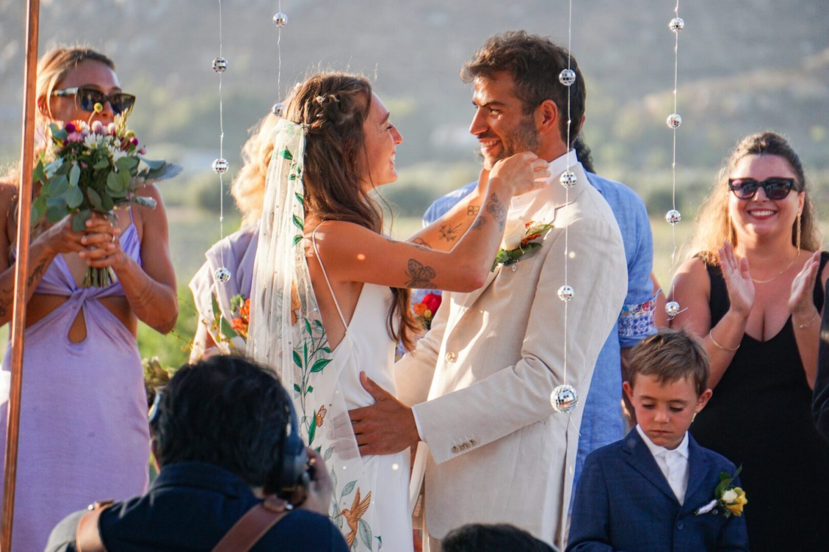 A bride and groom are holding hands in front of the crowd.